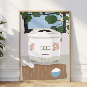 May include: A white rice cooker with floral designs on the side, sitting on a brown wooden surface with a white spoon and a bowl of rice. The background is a light purple wall with a window showing a green plant.