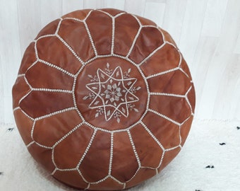 May include: A brown leather pouf with white stitching and a white embroidered star design.