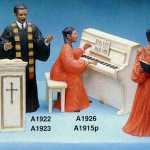 Puede incluir: Cinco figuritas que representan un coro y un pianista. Las figuras llevan todas túnicas rojas y están en posición de canto o de interpretación. Las figuritas están etiquetadas con los códigos de producto A1922, A1923, A1924, A1925, A1926 y A1915p.