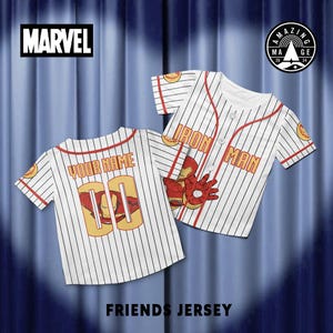 Peut inclure: Deux maillots de baseball blancs &agrave; fines rayures noires. L'un porte "YOUR NAME" et "00" au dos avec un graphisme Iron Man. L'autre dit "IRON MAN" avec un graphisme de main Iron Man. Le logo Marvel est en haut &agrave; gauche.