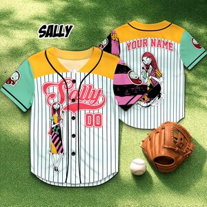 May include: White baseball jersey with black pinstripes, featuring a cartoon character design. The jersey has a yellow yoke, mint green sleeves, and the name "SALLY" in red script across the front. The number "00" is also displayed. A baseball glove and ball are next to the jersey.