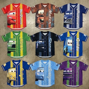 Puede incluir: Nueve camisetas de b&eacute;isbol con personajes de la pel&iacute;cula animada Cars. Cada camiseta tiene un esquema de color y dise&ntilde;o de personaje diferente, incluyendo McQueen, Mater, Hudson, y otros. Las camisetas tienen mangas cortas y botones frontales.