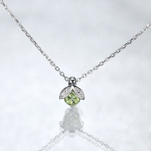 May include: A silver-toned necklace featuring a pendant shaped like a small insect or flower bud. The pendant has a central round light green gemstone accented by two small silver leaves encrusted with tiny clear stones on the upper portion.