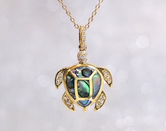 May include: A gold chain necklace with a gold turtle pendant. The turtle's shell is made of iridescent abalone and is accented with small clear stones.