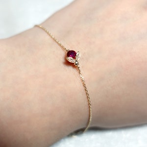 May include: A delicate gold chain bracelet with a small ruby and diamond bee charm.