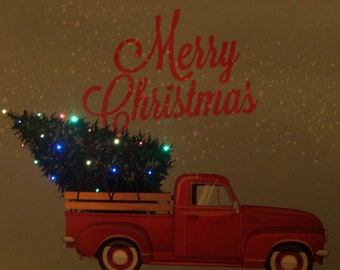 Old Fashioned Red Truck carrying Christmas tree with LED String Lights