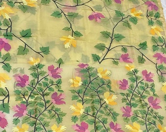 May include: A yellow sheer fabric with a floral pattern. The flowers are pink, yellow, and white. The fabric has a delicate, flowing texture.