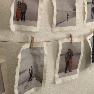 Puede incluir: Una serie de fotos de una pareja en varias poses, impresas en tela y colgadas con pinzas para la ropa. Las fotos tienen un estilo r&uacute;stico y vintage.
