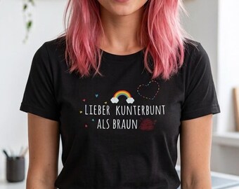 May include: A black short-sleeved t-shirt featuring a graphic print with a small rainbow, a dashed heart outline, and the white text "LIEBER KUNTERBUNT ALS BRAUN" centered on the chest, paired with blue denim jeans.