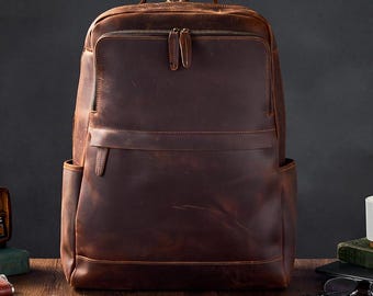 May include: A brown leather backpack with a zippered front pocket and two side pockets. The backpack has a distressed look and is made of high-quality leather.