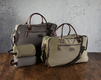 May include: A collection of travel bags in various sizes and colors. The bags are gray and olive green with brown leather accents. The bags have handles, zippers, and shoulder straps. The bags are on a wooden surface.