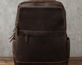 May include: A brown leather backpack with a large main compartment and a smaller front pocket. The backpack has a zipper closure and adjustable straps.