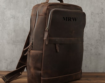 May include: A brown leather backpack with a zippered front pocket and the initials "MRW" embossed on the front.