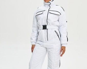 Könnte beinhalten: Weißer Ski-Overall mit schwarzem Besatz und Gürtel. Der Overall hat einen Reißverschluss und Taschen.