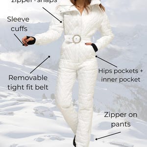 May include: White quilted ski jumpsuit with a high collar, a removable belt, and zippered pockets. The jumpsuit has a 2-step closing system with a zipper and snaps. The model is wearing a red beret.