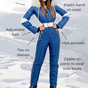 K&ouml;nnte beinhalten: Ein blauer Ski-Overall mit einer wei&szlig;en, pelzbesetzten Kapuze, einem verstellbaren G&uuml;rtel und Rei&szlig;verschlusstaschen. Der Overall hat B&auml;nder an den &Auml;rmeln und einen Rei&szlig;verschluss an der Hose, um ihn &uuml;ber Stiefel zu tragen. Das Model tr&auml;gt schwarze Stiefel.