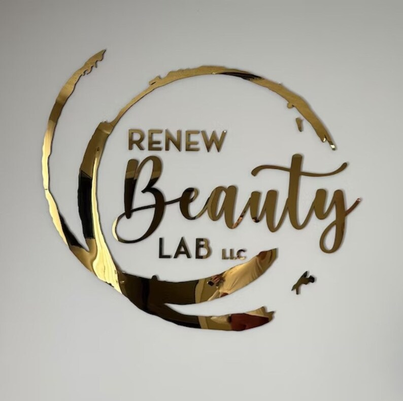 以下が含まれることがあります： 円形のデザインと「RENEW Beauty LAB LLC」というテキストが書かれた金色のロゴ