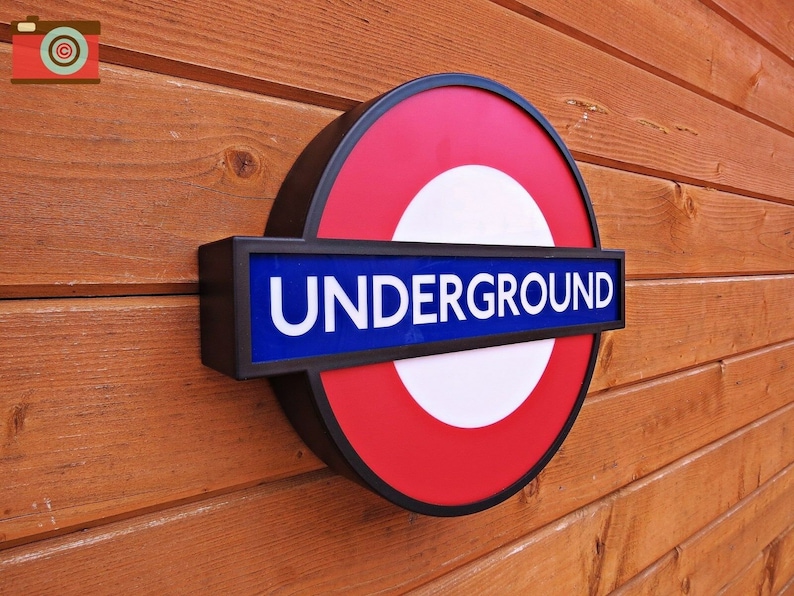 May include: A red, white, and blue London Underground sign with the word "UNDERGROUND" in white letters on a blue background.
