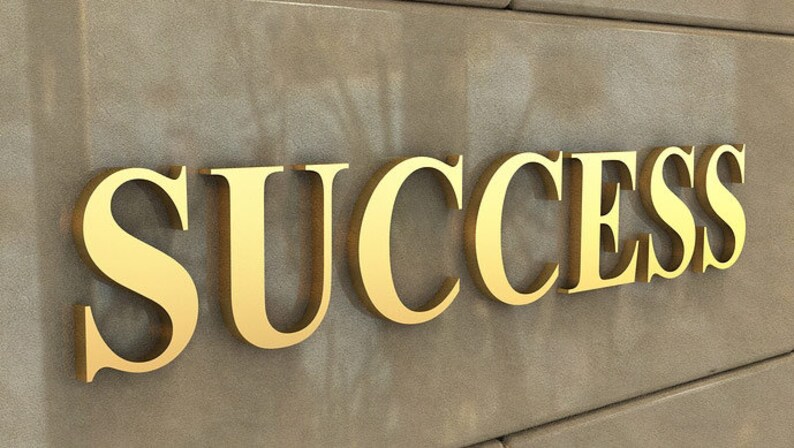 Puede incluir: La palabra "SUCCESS" en letras doradas sobre una pared de textura marr&oacute;n.