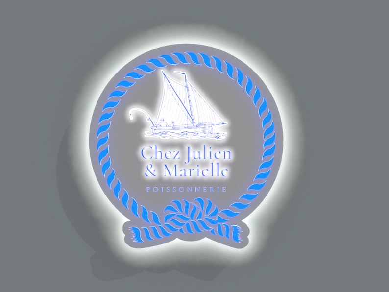 May include: A white circle with a blue rope border and a white sailboat illustration inside. The text "Chez Julien & Marielle POISSONNERIE" is written in black below the sailboat.
