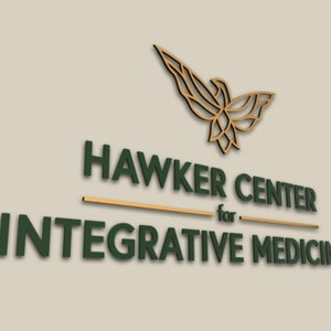 Puede incluir: Un logotipo de p&aacute;jaro estilizado dorado sobre el texto "Hawker Center for Integrative Medicine" en letras 3D verdes.