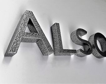 May include: Black metal letters spelling out the word "ALSO" on a white background.