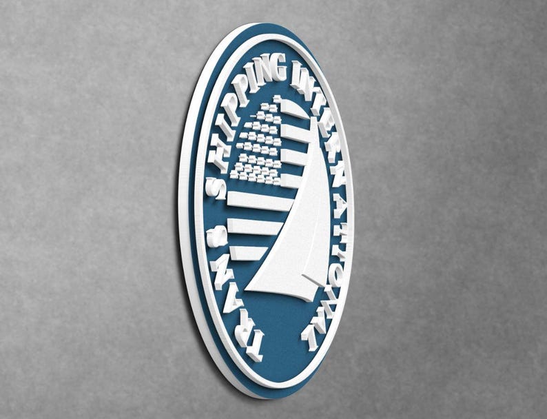 May include: An oval-shaped wall sign featuring a deep blue background with a white border. The sign displays a white graphic of a sailboat and the text TRANS SHIPPING INTERNATIONAL in raised white lettering encircling the central design.