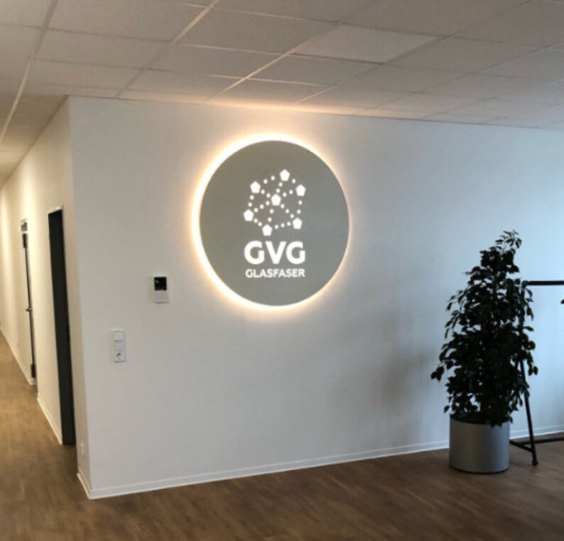 May include: A white circular sign with a glowing halo around the edge. The sign has a white logo with a network of connected dots and the text "GVG GLASFASER".