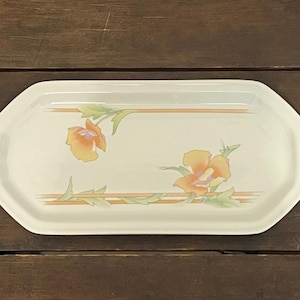 May include: Cream-colored rectangular serving platter with a floral design. The platter features two orange and yellow flowers with green leaves and brown stripes. The edges are slightly angled.