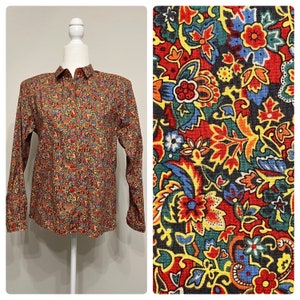May include: A long-sleeved button-down shirt with a colorful paisley print. The shirt has a classic collar and a button-up front.