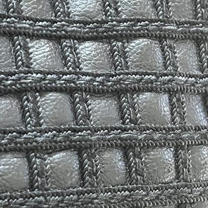 May include: A black material featuring a grid pattern created by raised, braided cord trim. The square sections between the cords have a textured, pebbled surface, creating a repeating geometric design across the entire surface of the item.