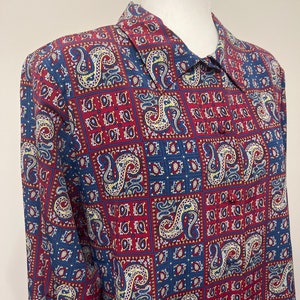May include: A long-sleeved button-up shirt with a paisley pattern in shades of blue, red, and yellow.