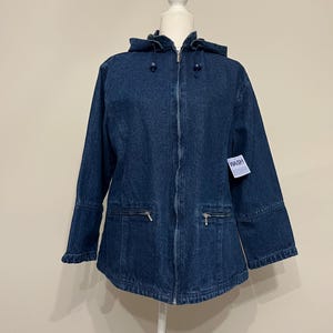 May include: A dark blue denim jacket with a hood, zipper closure, and two front pockets. The jacket is displayed on a white mannequin. The tag on the jacket reads "WASH".
