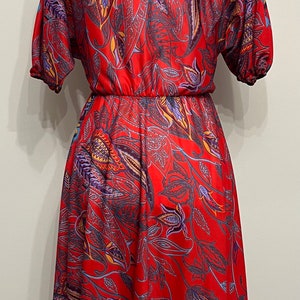 May include: A red dress with a floral print featuring blue, purple, and yellow accents. The dress has a fitted bodice and a flowing skirt.