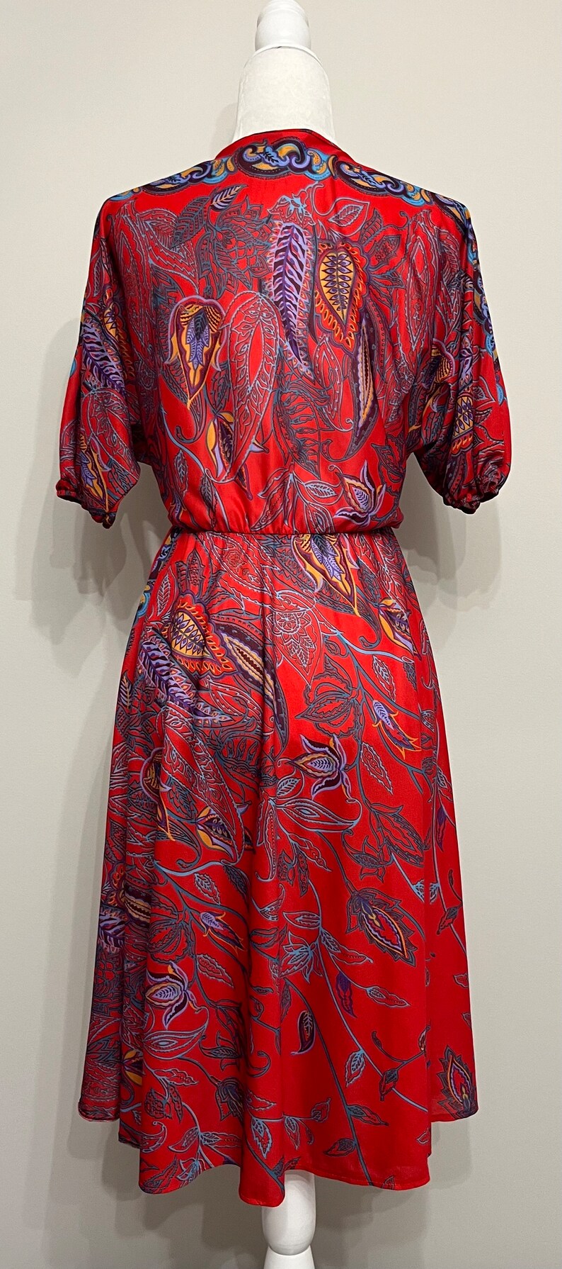 May include: A red dress with a floral print featuring blue, purple, and yellow accents. The dress has a fitted bodice and a flowing skirt.