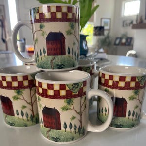 May include: Set of five ceramic coffee mugs. Each mug features a red barn scene with trees and a checkered pattern in red, cream, and green. The mugs have white handles and a cream-colored interior.