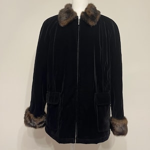 May include: A black velvet jacket with a brown fur collar and cuffs. The jacket has a zipper closure and two pockets.