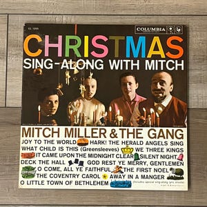 May include: Vintage Christmas album cover featuring Mitch Miller & The Gang. The album cover has the word "CHRISTMAS" in colorful letters. The album cover also includes the text "SING-ALONG WITH MITCH" and a list of Christmas carols.