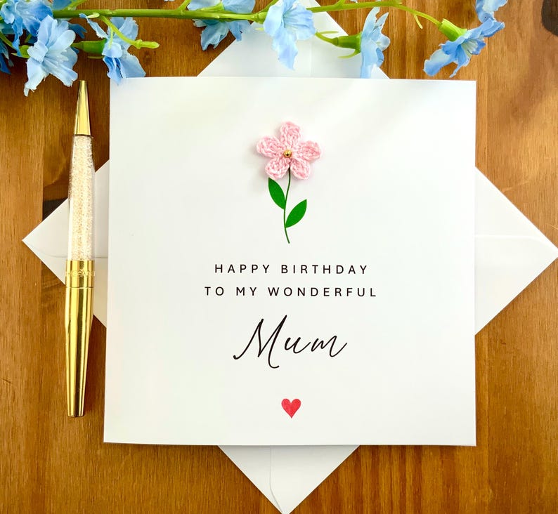 K&ouml;nnte beinhalten: Eine wei&szlig;e Karte mit einer rosa Papierblume und dem Text "Alles Gute zum Geburtstag an meine wundervolle Mama" mit einem roten Herzen.