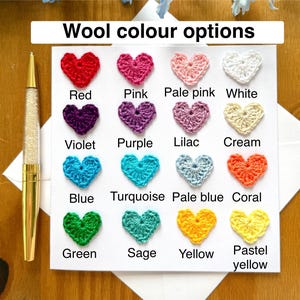 May include: A card with a chart of crocheted hearts in various colors, including red, pink, pale pink, white, violet, purple, lilac, cream, blue, turquoise, pale blue, coral, green, sage, yellow, and pastel yellow. The text "Wool color options" is at the top of the card.