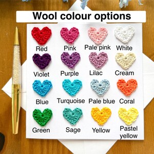 May include: A card with a chart of crocheted hearts in various colors, including red, pink, pale pink, white, violet, purple, lilac, cream, blue, turquoise, pale blue, coral, green, sage, yellow, and pastel yellow. The text "Wool color options" is at the top of the card.