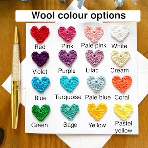 Puede incluir: Una tarjeta con una tabla de corazones tejidos a crochet en varios colores, incluyendo rojo, rosa, rosa p&aacute;lido, blanco, violeta, morado, lila, crema, azul, turquesa, azul p&aacute;lido, coral, verde, salvia, amarillo y amarillo pastel. El texto "Wool color options" est&aacute; en la parte superior de la tarjeta.