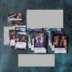 May include: A collection of Star Wars tabletop game cards featuring character portraits of Han Solo, Mon Mothma, and Admiral Motti, alongside ship cards like the Modified Pelta-class Assault Ship and Interdictor Combat Refit with text.