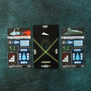 Puede incluir: Tres cartas de juego de Star Wars con destructores estelares. Las cartas muestran gráficos detallados, incluyendo esquemas de naves, valores numéricos y el texto "IMPERIAL F-CLASS STAR DESTROYER" y "IMPERIAL II-CLASS STAR DESTROYER". La tarjeta central tiene una silueta de nave espacial.