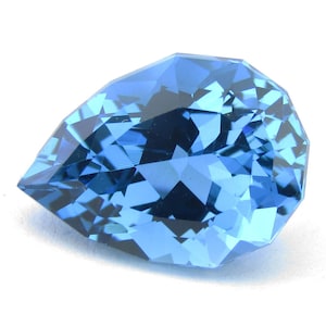 May include: A pear-shaped gemstone with a vibrant blue color and a faceted surface. The stone features numerous triangular and quadrilateral facets that create a complex pattern of light reflection and deep blue tones throughout the entire piece.