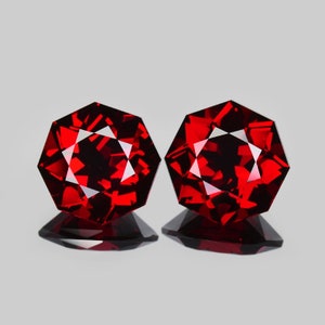 May include: Two deep red octagon-shaped gemstones with a faceted cut.