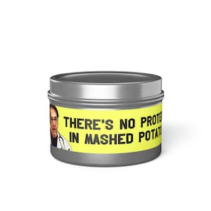 May include: A silver tin container with a yellow label that reads "THERE'S NO PROTEIN IN MASHED POTATOES". A man with a white coat and stethoscope is pictured on the label.
