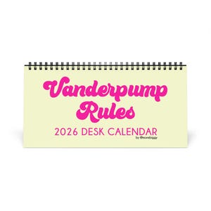 May include: A desk calendar with a spiral binding, featuring the text "Vanderpump Rules" in pink script. The calendar is labeled "2026 DESK CALENDAR" in a sans-serif font, with the creator's name at the bottom.