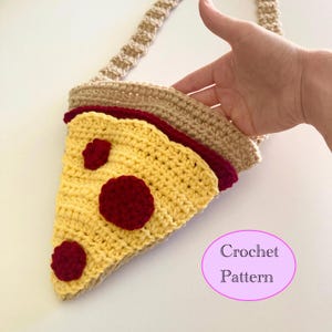 Puede incluir: Un bolso tejido a ganchillo con forma de porción de pizza, con una correa beige. La pizza presenta una corteza amarilla, salsa roja y tres pepperoni rojos. El bolso está hecho a mano y tiene el texto "Crochet Pattern" en un óvalo rosa.