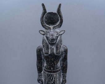 May include: Black stone statue of an Egyptian god with a bull's head, wearing a crown with horns and a sun disk. The statue is standing on a base with hieroglyphs.